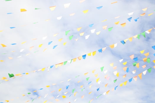 Blue,green, yellow, white triangle flags are on lines and sky background with clouds. photo