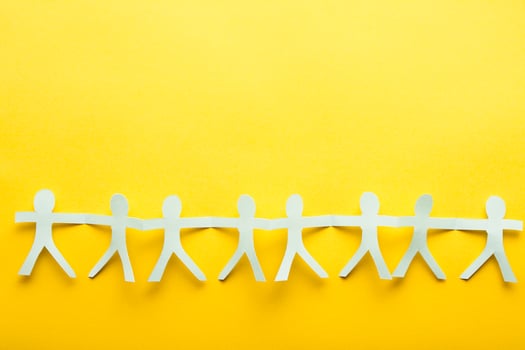Light blue paper people on yellow background. Friendship flatlay concept. photo