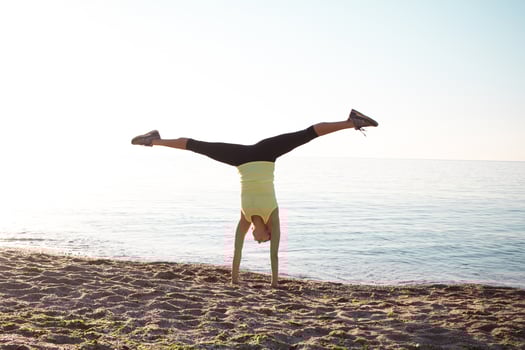 young professional gymnast woman dance on the beach, training exercises with cool junps, sunrise in sea or ocean background photo