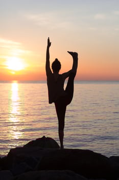 fitness mixed race asian woman in yoga pose on the morning beach, beautiful fit woman practice fitness exrxise stones, morning sea or ocean background photo