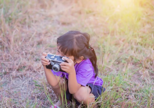Woman with camera hiding behind the tree photo