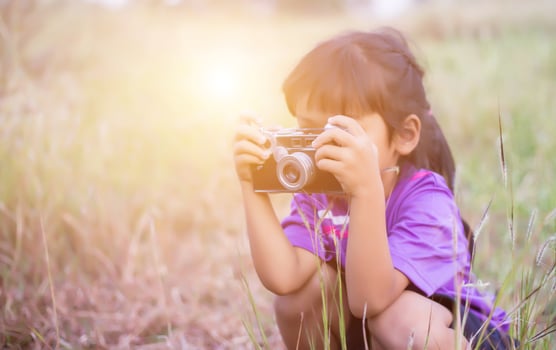 Woman with camera hiding behind the tree photo