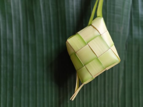 Ketupat or rice dumpling is a local delicacy during the festive season. Ketupats, a natural rice casing made from young coconut leaves for cooking rice isolated on a white background photo