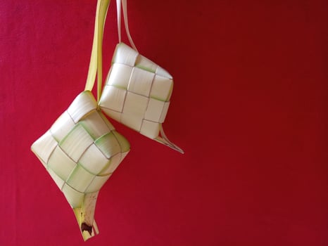 Ketupat, Indonesian rice dumpling on red background. Ketupat is a natural rice casing made from young coconut leaves for cooking rice during eid Mubarak, Eid ul Fitr photo