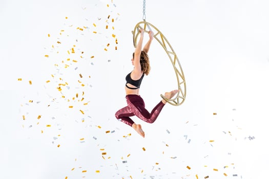 Woman hanging in aerial silk in white studio photo