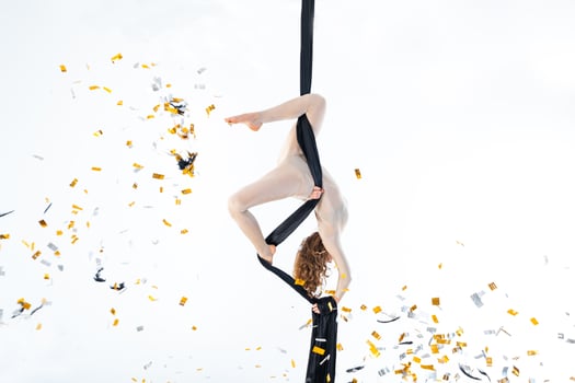 Woman hanging in aerial silk in white studio photo