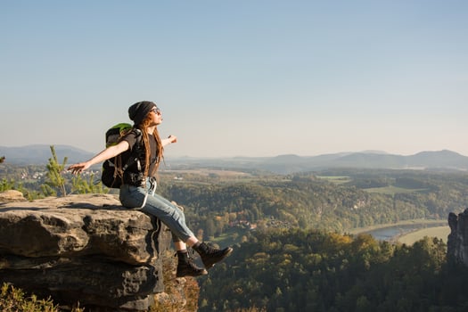 Youmg woman with backpack stand on the old german castle in saxon switzerland national park photo