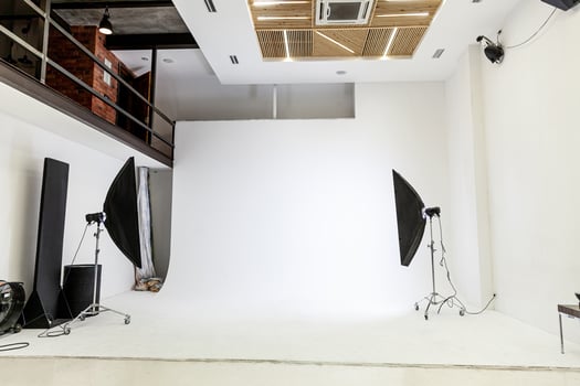 Empty photo studio with lighting equipment. Photographer workplace interior with professional tool set gear. Flash light white background scenes ready for studio shooting. Modern photographer studio