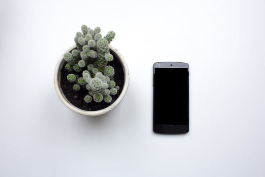 black cellphone on white background, top view of smartphone and interior decorations photo