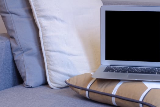 laptop in bedroom with bed, lamp and home decor background. photo