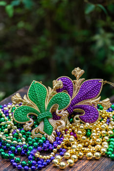Mardi Gras color beads with fleur de lis on wooden table in sunlight photo