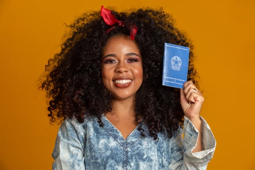 Beautiful curly-haired girl holding a work card. On yellow background. photo