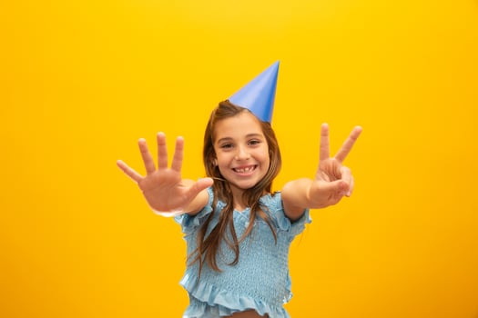 Cute little girl celebrates birthday. Seven years old. Closeup portrait on yellow background. photo