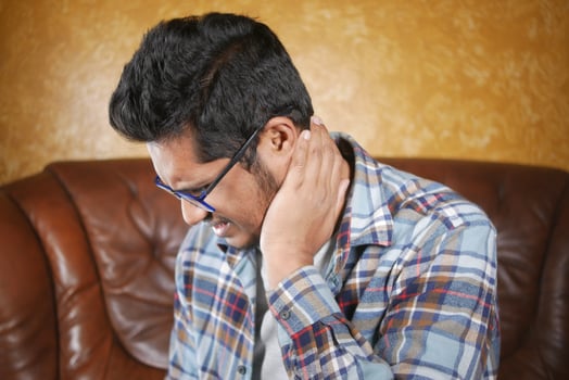 man suffering chronic neck pain while sitting on sofa photo