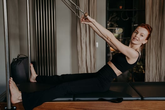 Young beautifull woman with smile doing exercises on pilates reformer photo