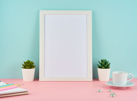 Mockup with blank white frame, plant cactus, cup of coffee or tea on pink table photo