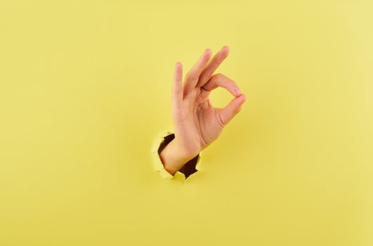 Woman showing a sign of agreement on yellow background copy space closeup photo