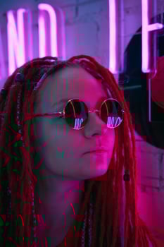 Girl in neon lights, beautiful woman in sunglasses, with pink hair, with dreadlocks pigtails photo