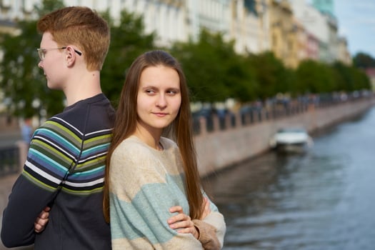 portrait of a happy couple, standing back to back in the city center, red-haired man in glasses, beautiful woman with long dark hair photo