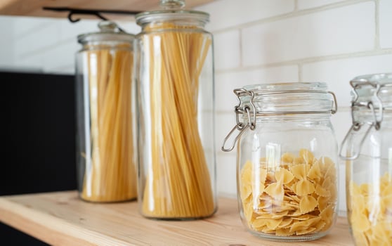 Wheat Italian pasta in glass jar on a wooden shelf in the kitchen. photo