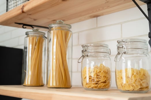 Wheat Italian pasta in glass jar on a wooden shelf in the kitchen. photo