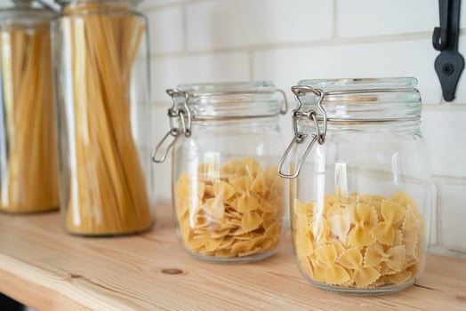 Wheat Italian pasta in glass jar on a wooden shelf in the kitchen. photo