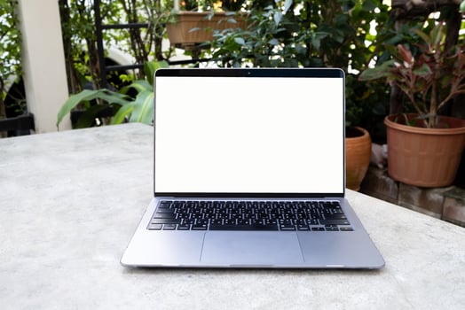 Laptop with white blank screen on white table. Online work from home and work anywhere concept. Garden home background. photo