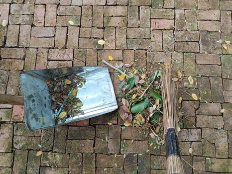 Sweeping dry leaves with broom, garden, Maintenance worker in park garden cleans the roads photo