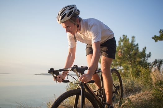 Bicycle rider on professional cyclocross bike ride downhill, pine and lake background photo