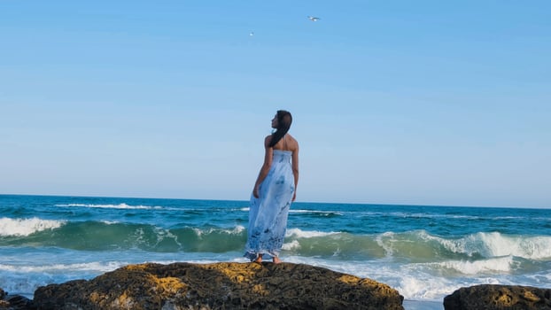 Young beautiful woman dressed in a white dress walk barefoot on the summer beach photo