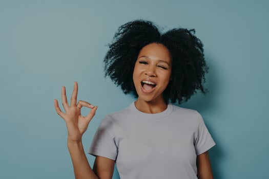Pretty girl of mixed race appearance showing ok gesture with fingers and winks photo