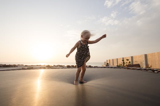 little girl jump and having good time on trampoline in summer time photo