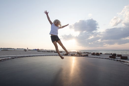 little girl jump and having good time on trampoline in summer time photo