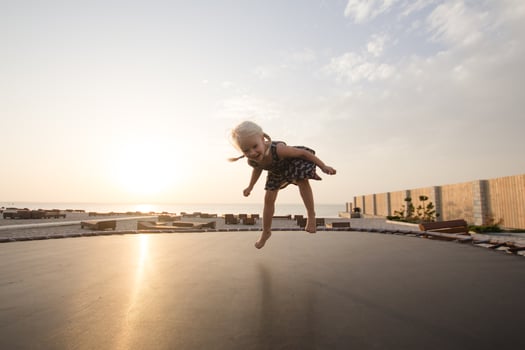 little girl jump and having good time on trampoline in summer time photo