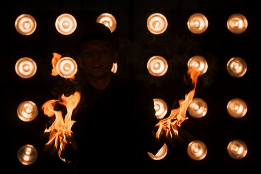 Dangerous beauty of the fire in the hands. Professional magician showing trick. Light bulbs on background photo