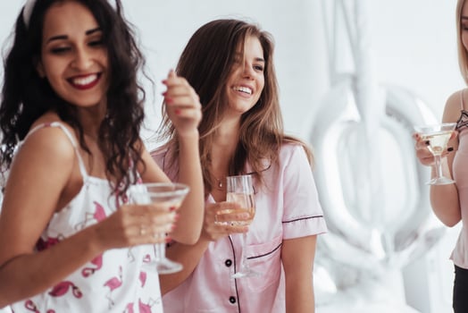 Happy day. Celebrating bachelorette in white bedroom. Girls smiles and drink champagne photo