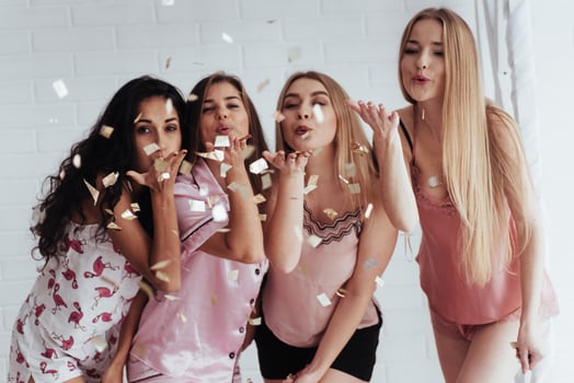 It's air kisses for you. Confetti in the air. Young girls have fun on the white bed in nice room photo