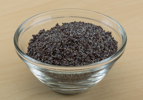 Poppy seeds in a bowl on wooden background photo