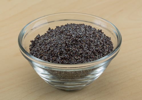 Poppy seeds in a bowl on wooden background photo