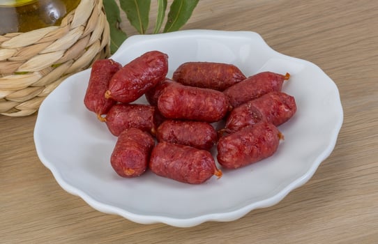 Mini salami on the plate and wooden background photo