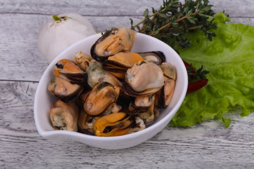 Pickled mussels in the bowl served pepper, garlic and salad photo