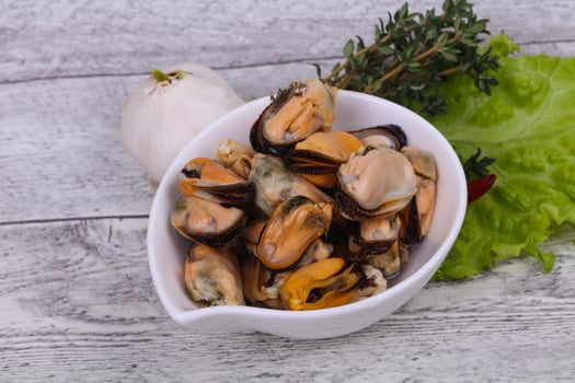 Pickled mussels in the bowl served pepper, garlic and salad photo
