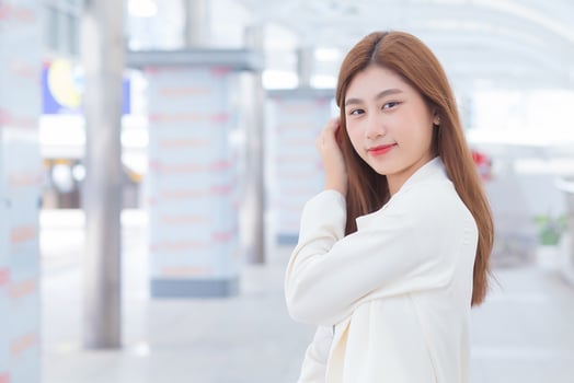 Young Asian working woman looking at camera in white is out to meet a client at the office in a happy mood. photo