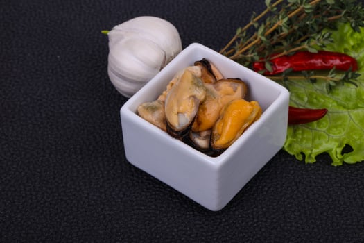 Pickled mussels in the bowl served pepper, garlic and salad photo