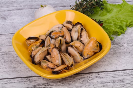 Pickled mussels in the bowl served pepper, garlic and salad photo