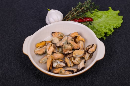 Pickled mussels in the bowl served pepper, garlic and salad photo