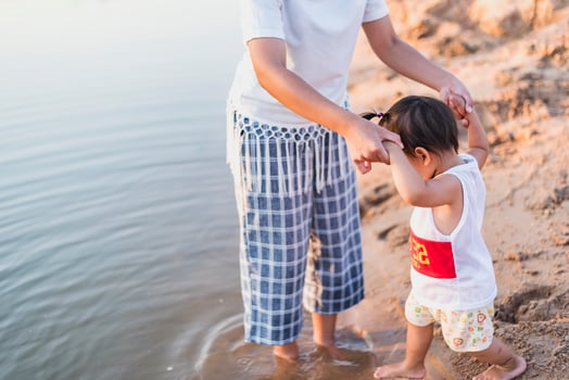 A young mother plays with her 2-5 year old daughter on the beach in summer. Outdoor resort on the lake Have a good rest on weekends, family days. photo