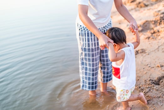 A young mother plays with her 2-5 year old daughter on the beach in summer. Outdoor resort on the lake Have a good rest on weekends, family days. photo