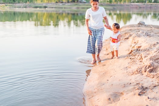 A young mother plays with her 2-5 year old daughter on the beach in summer. Outdoor resort on the lake Have a good rest on weekends, family days. photo
