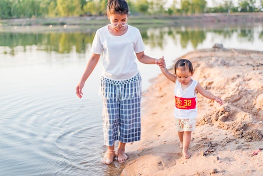 A young mother plays with her 2-5 year old daughter on the beach in summer. Outdoor resort on the lake Have a good rest on weekends, family days. photo
